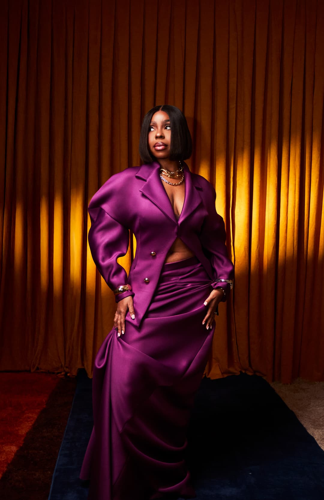 LADY IN A PURPLE SUIT STOOD IN FRONT OF GOLDEN YELLOW BACKDROP